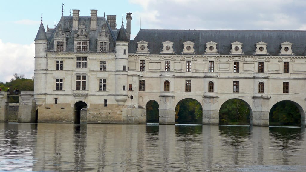 The majestic Château de Chenonceau spanning the River Cher in the Loire Valley, France. This Renaissance masterpiece, with its white façade and graceful arches reflecting on the calm waters, embodies the elegance of French architecture and history.