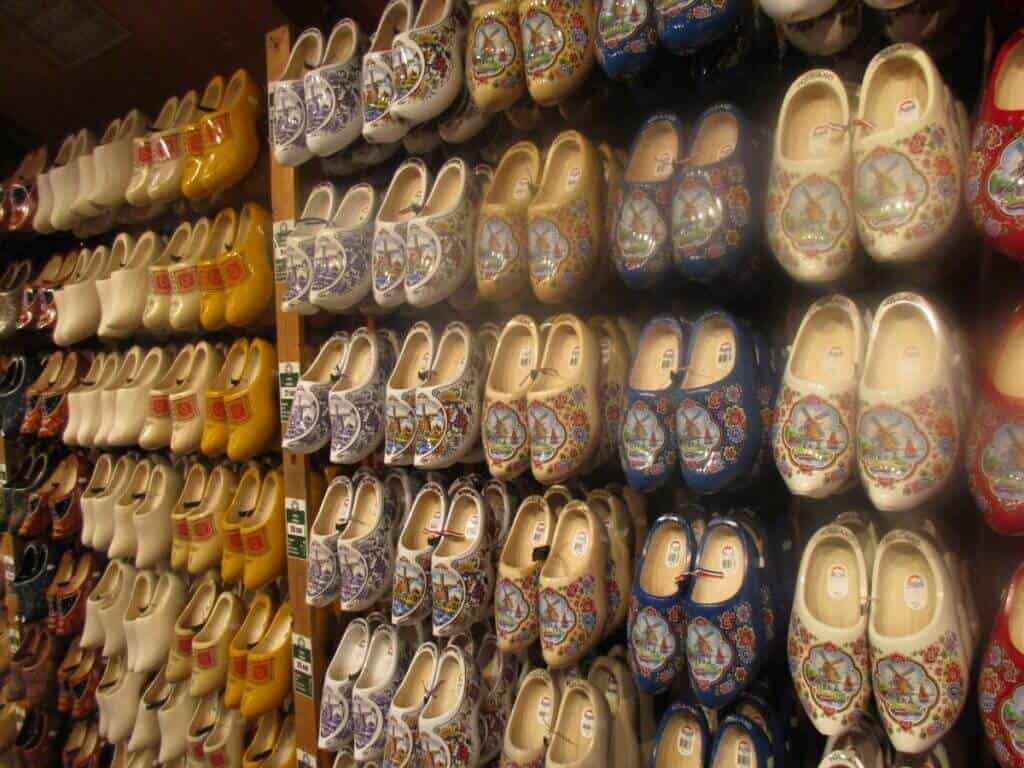 A vibrant display of traditional Dutch wooden shoes, also known as clogs, in a Zaanse Schans shop. The clogs are ornately painted with various designs and patterns, highlighting an important aspect of Dutch cultural attire and craftsmanship.